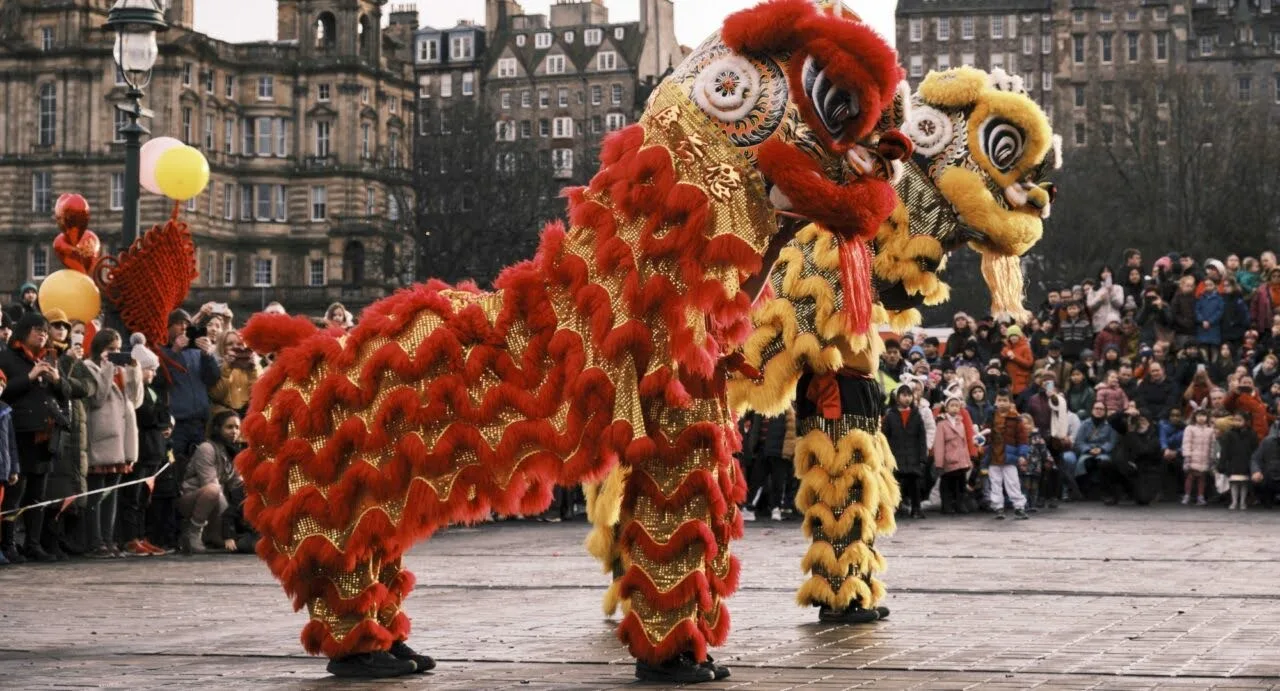 A red and a yellow lion performing in front of a big crowd in Edinburgh